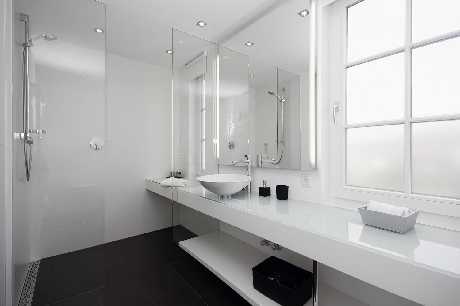 A modern bathroom with a glass shower enclosure, a white sink, and a large mirror.