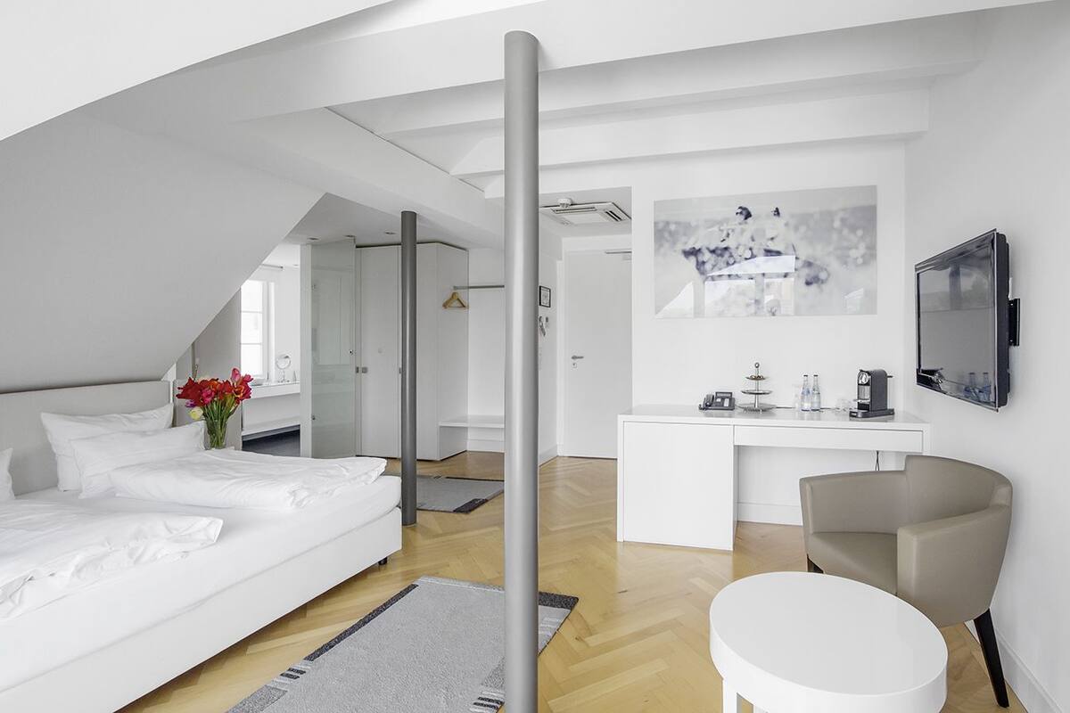 Una habitación de hotel moderna con una cama grande, un escritorio, una silla y un televisor.