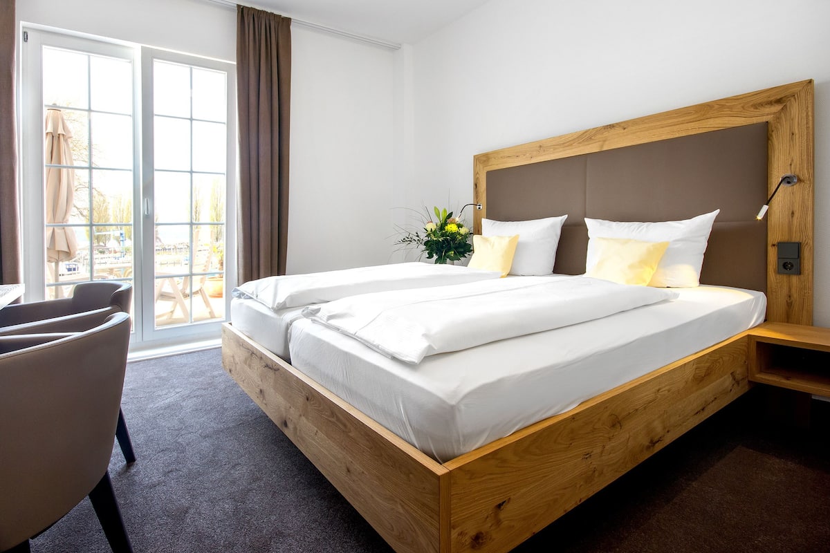 Una cama doble con cabecera de madera, una mesita de noche pequeña y una silla.