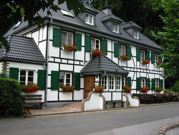 Un edificio tradicional de entramado de madera con contraventanas verdes y jardineras con flores.