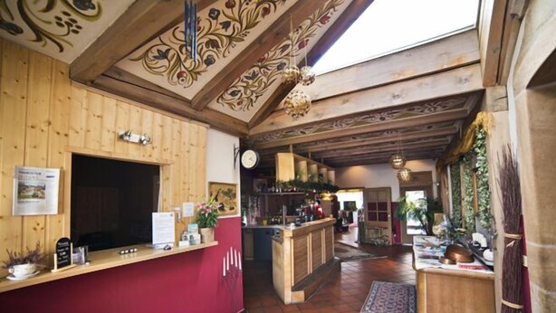 A wooden interior with a reception desk, a clock, and a decorative ceiling. - Hotel Gasthof Zur Linde (Hessdorf)