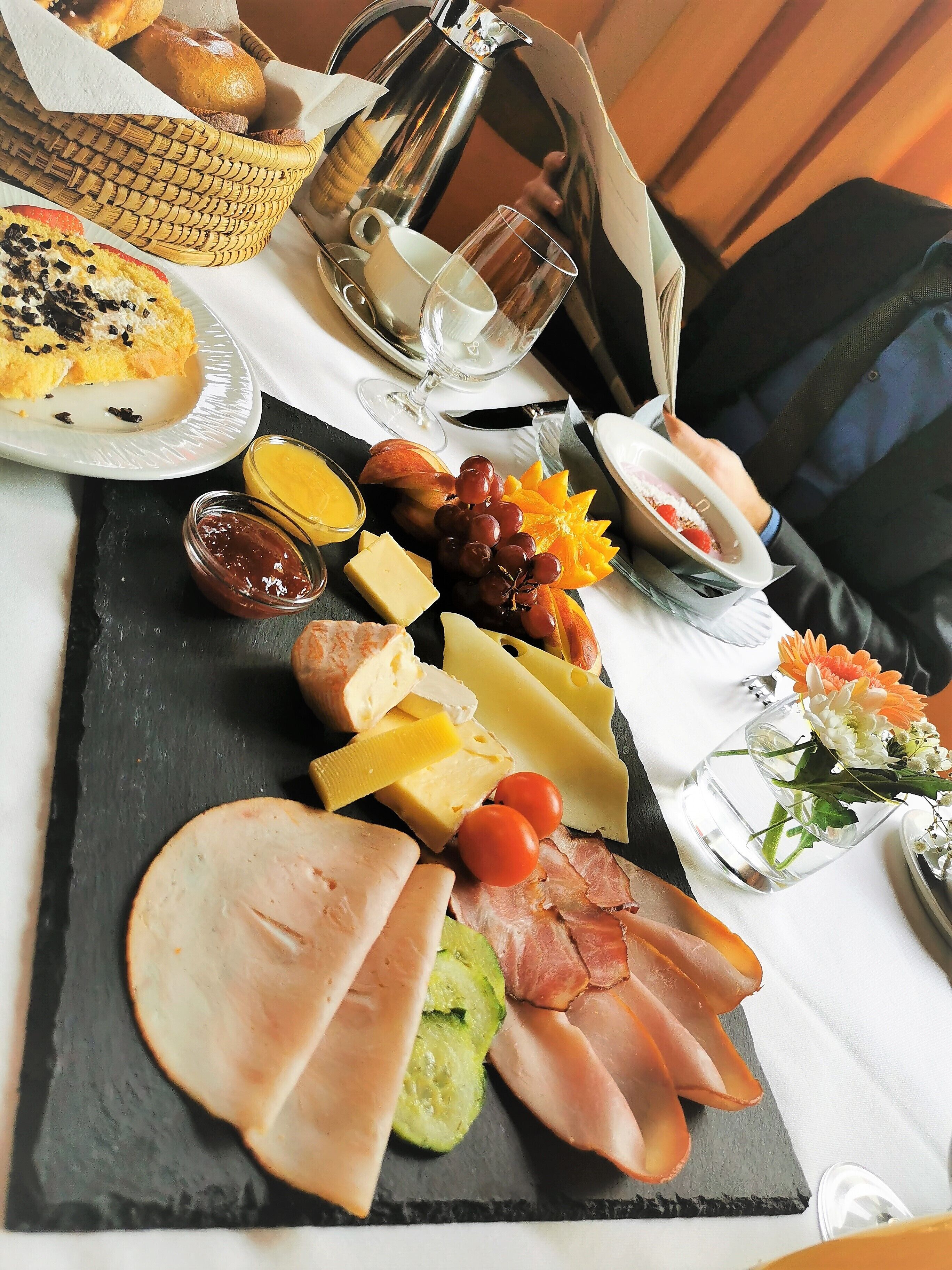 A charcuterie board with various cheeses, meats, fruits, and a coffee pot.