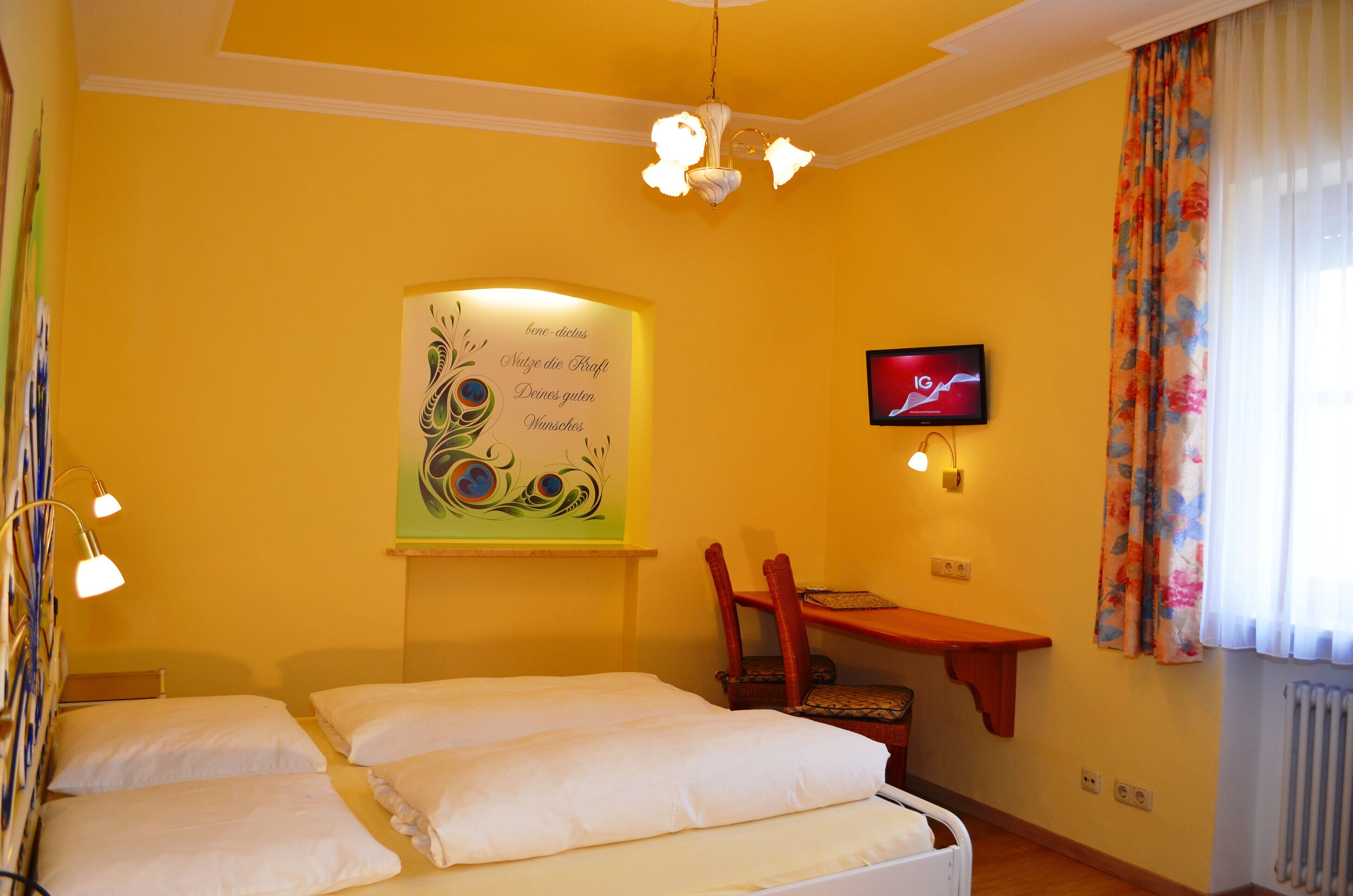 A hotel room with two beds, a desk, a chair, a television, and a decorative wall piece.