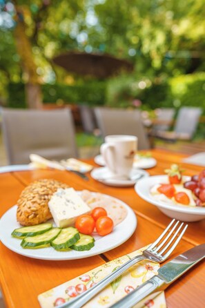 A table set for a meal with plates of food, a cup, and cutlery. - Hotel Plankl (Altötting)