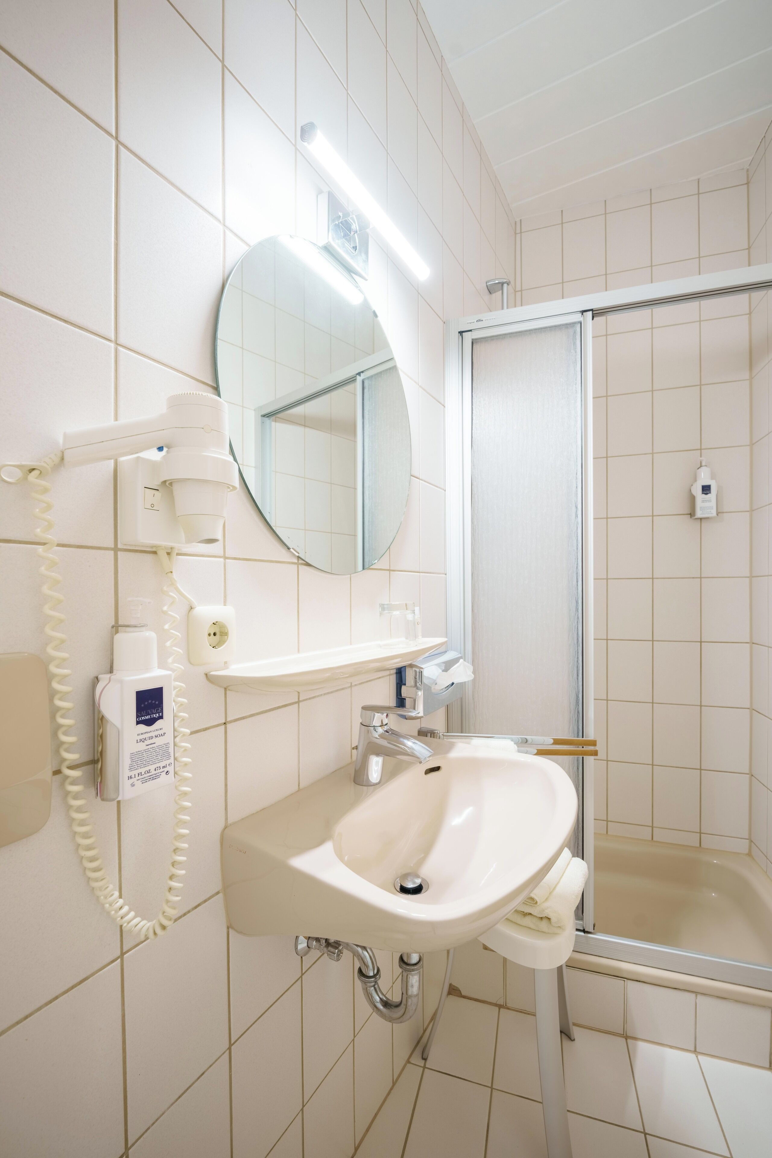 A bathroom with a sink, mirror, and shower.
