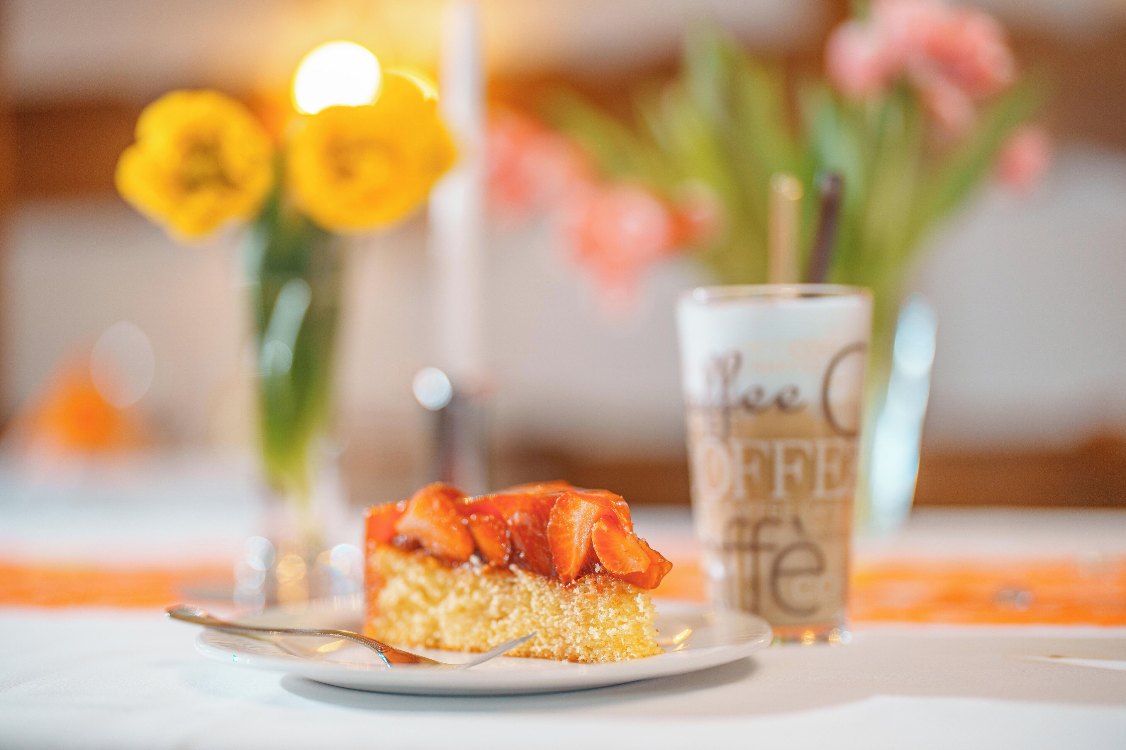 Un postre en un plato, con una taza de café al fondo.