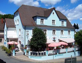 Um edifício azul claro com telhado castanho, com restaurante e café no andar térreo.