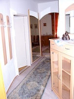 Quarto com um armário de madeira, um espelho e um tapete estampado.