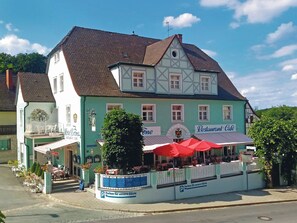 Un edificio tradicional con entramado de madera con un restaurante llamado 'Restaurant-Café' y un cartel que indica 'Parken für unsere Gäste' (Estacionamiento para nuestros huéspedes).