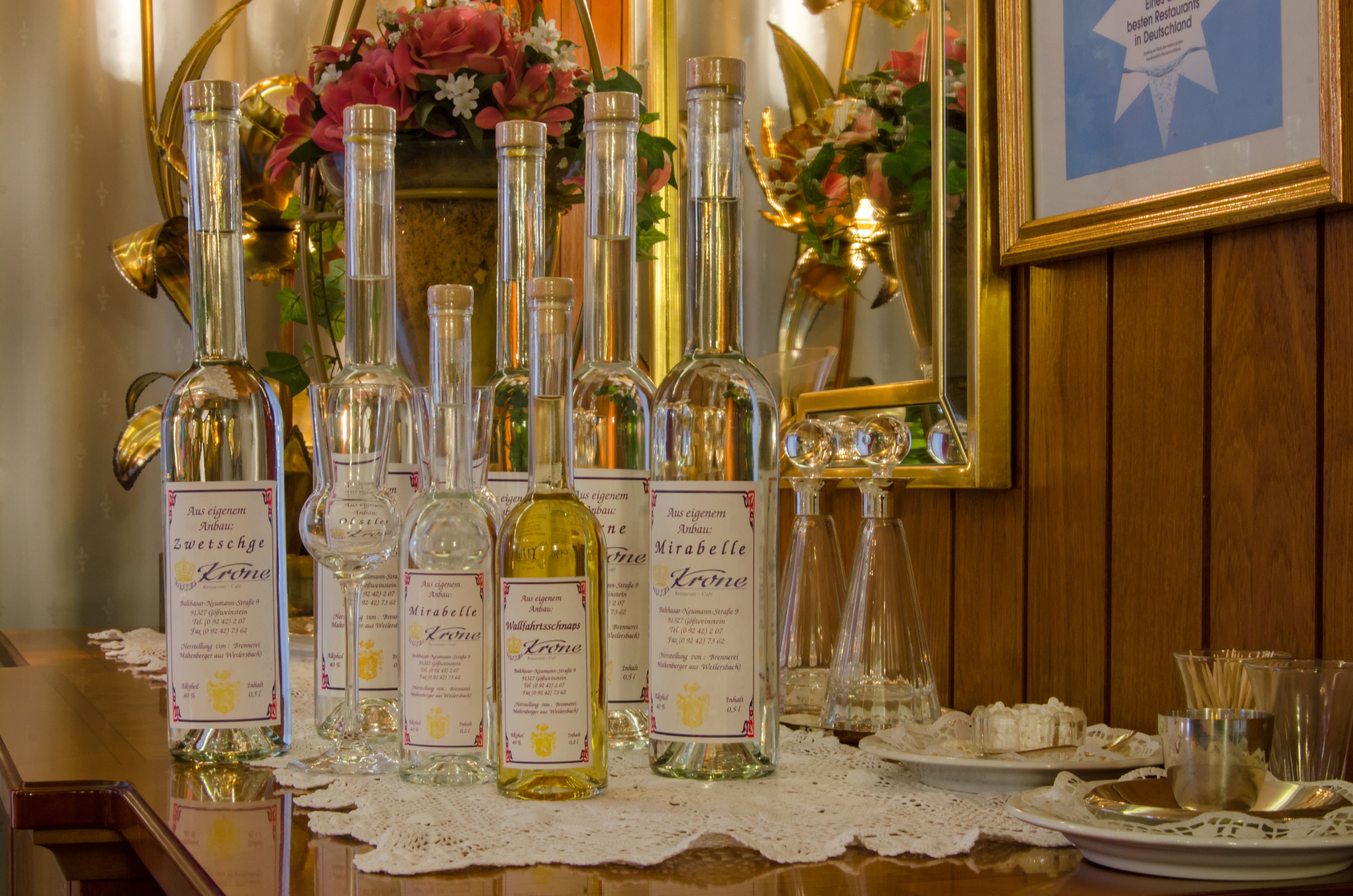 Una mesa con varias botellas de vino y copas, rodeada por un mantel de encaje.