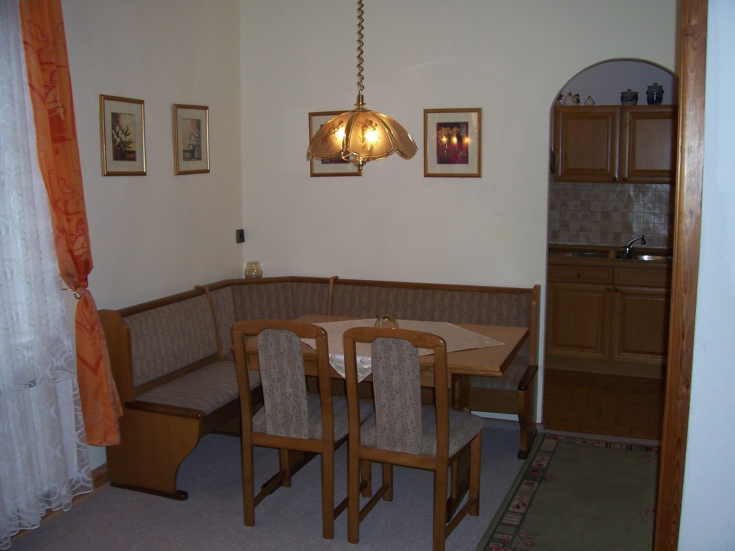 Zona pranzo con tavolo e sedie in legno, una panca e un lampadario.