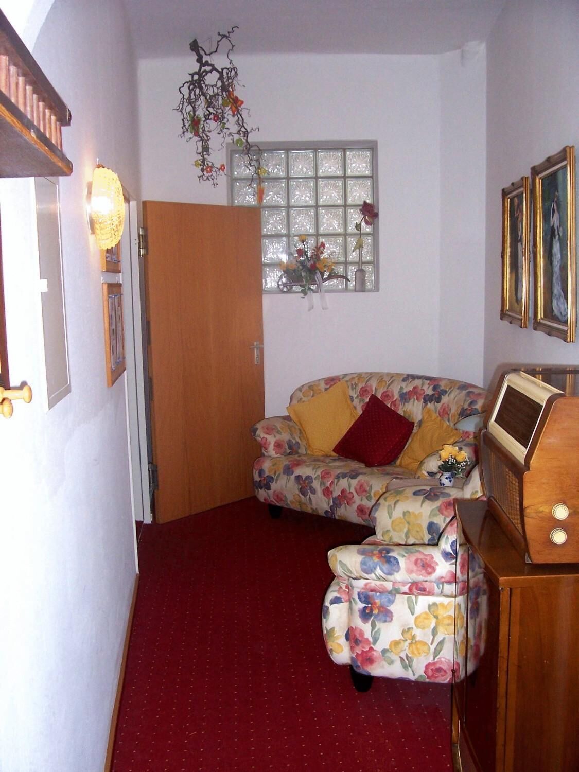 Un salón acogedor con un sofá floral, un mueble de madera y una radio antigua.