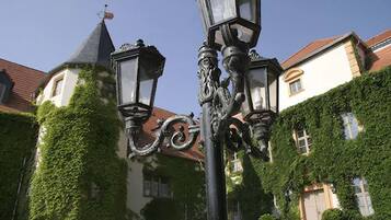 A street lamp with ornate designs, a building with a pointed roof, and ivy-covered walls.
