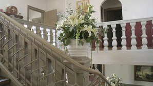 Una imponente escalera con barandilla blanca, un arreglo floral colgante y un cuadro en la pared.