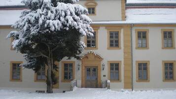 Un edificio cubierto de nieve, con múltiples ventanas y una entrada central.