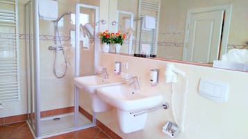 Un bagno con doccia vetrata, due lavandini, uno specchio e un WC.