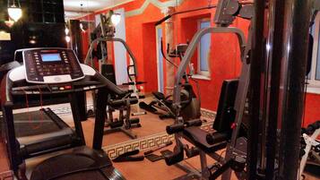 A gym with treadmills, weight machines, and a mirrored wall.