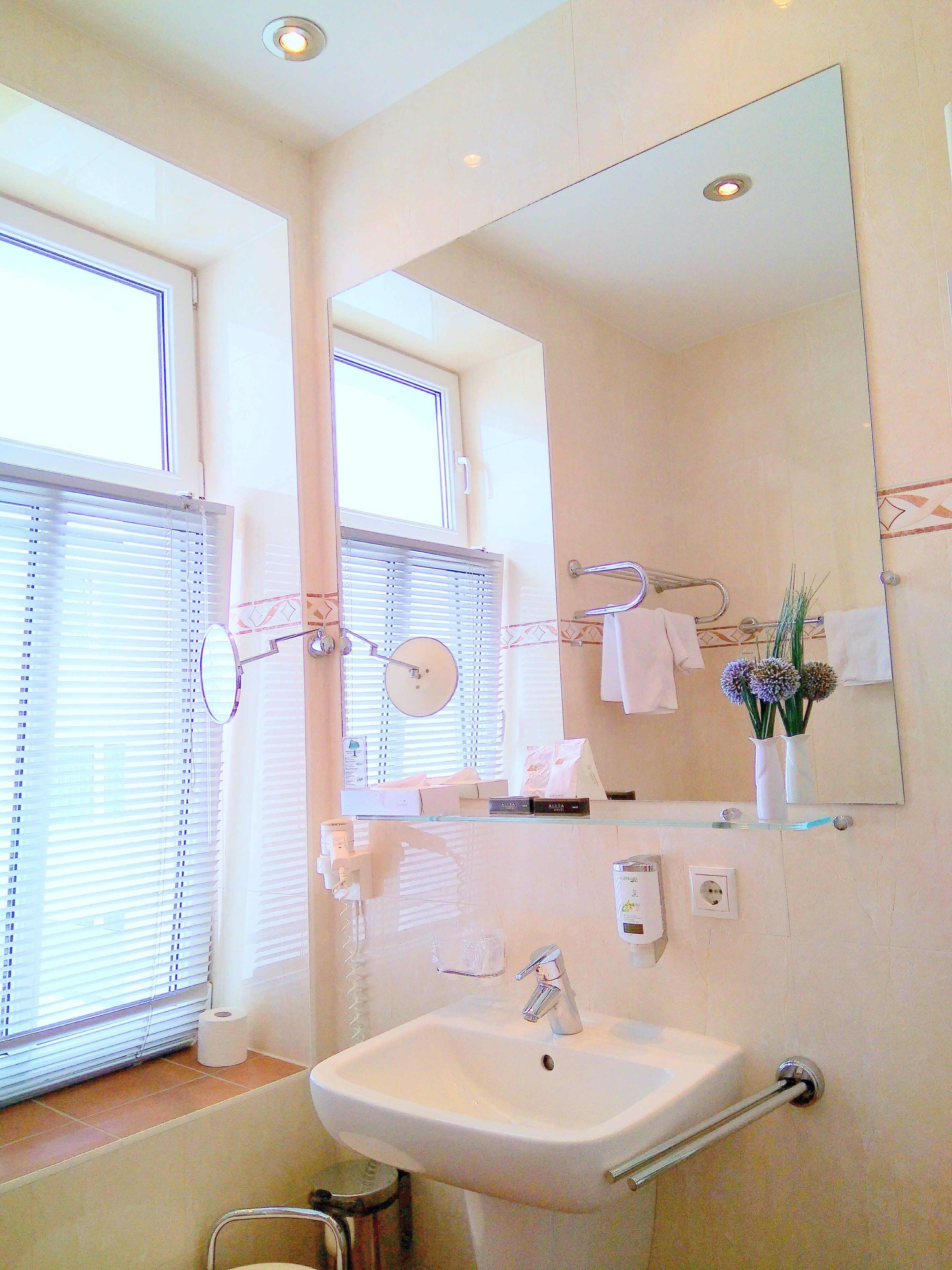 A bathroom with a sink, mirror, and window with blinds.
