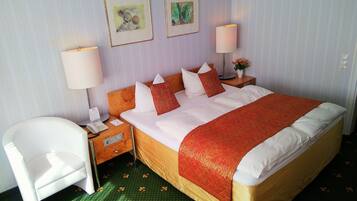 Una habitación de hotel con una cama, una silla, dos mesitas de noche y dos lámparas de pared.