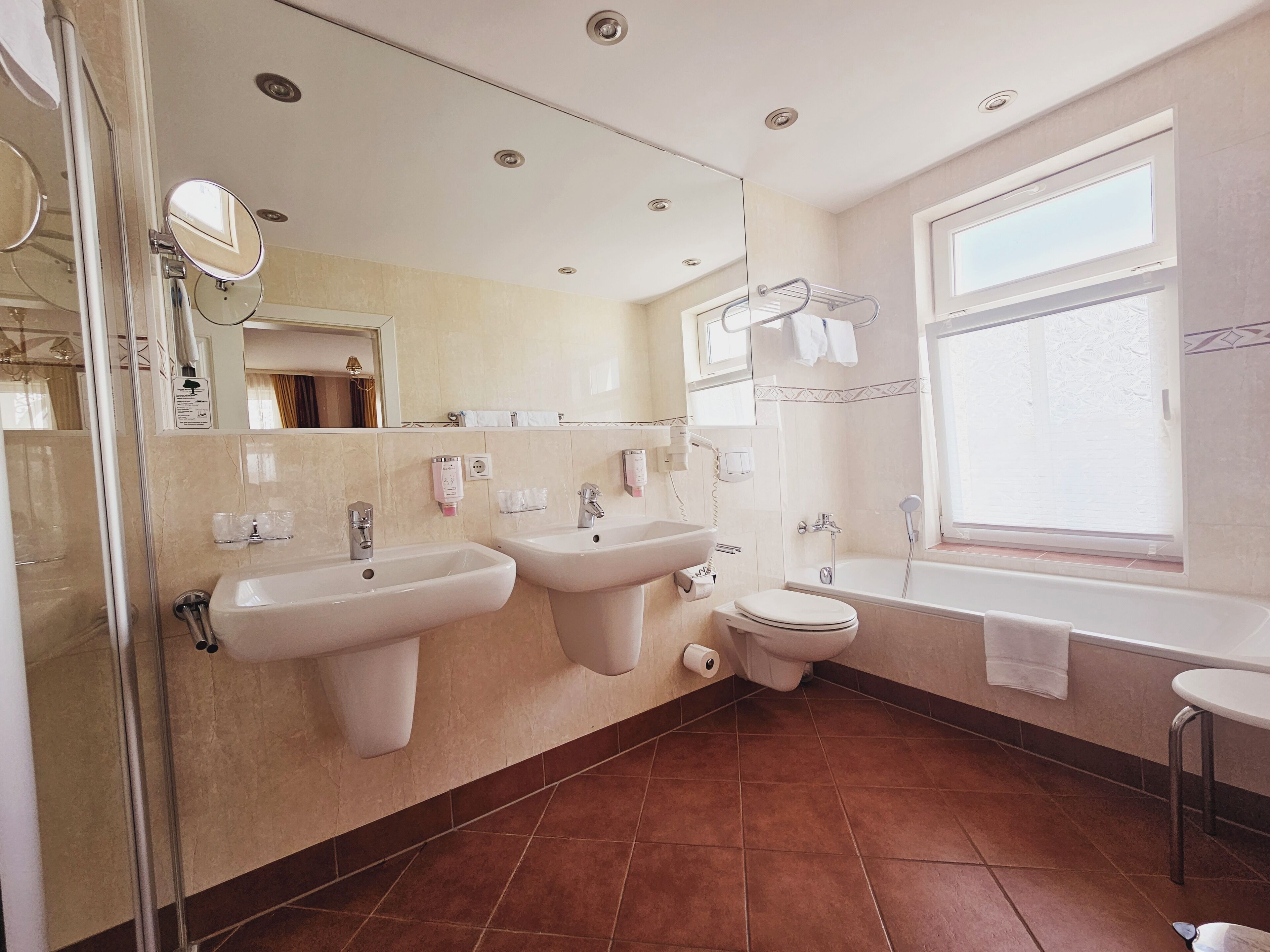 A modern bathroom with two sinks, a toilet, and a bathtub.