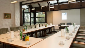 A conference room with long tables, chairs, and various amenities like cups, bottles, and a projector. - Hotel Mönter-Meyer (Bad Laer)