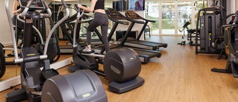 Un gimnasio con cintas de correr, elípticas y equipo de pesas.