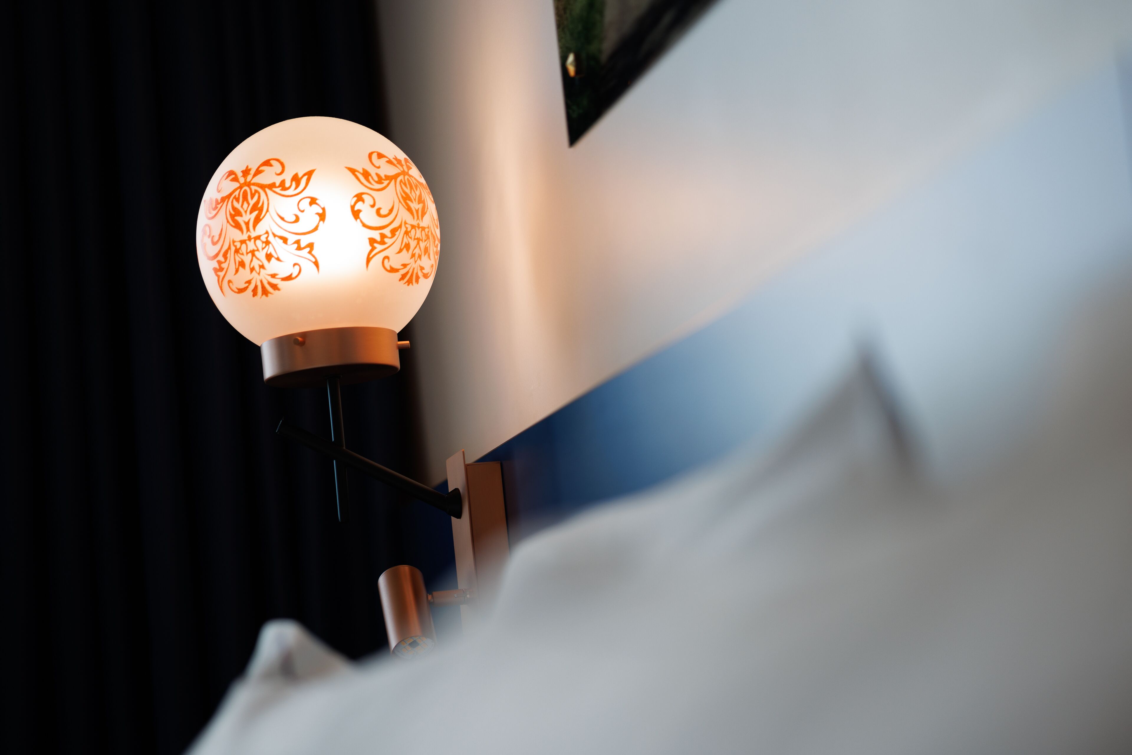 En lampe med en dekorativ glasskærm på et natbord.