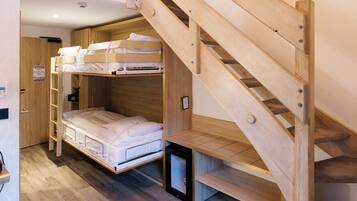 Un lit superposé avec une échelle en bois, un bureau et une petite étagère.
