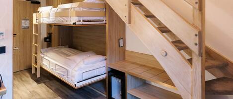 A bunk bed with a wooden ladder, a desk, and a small shelf.
