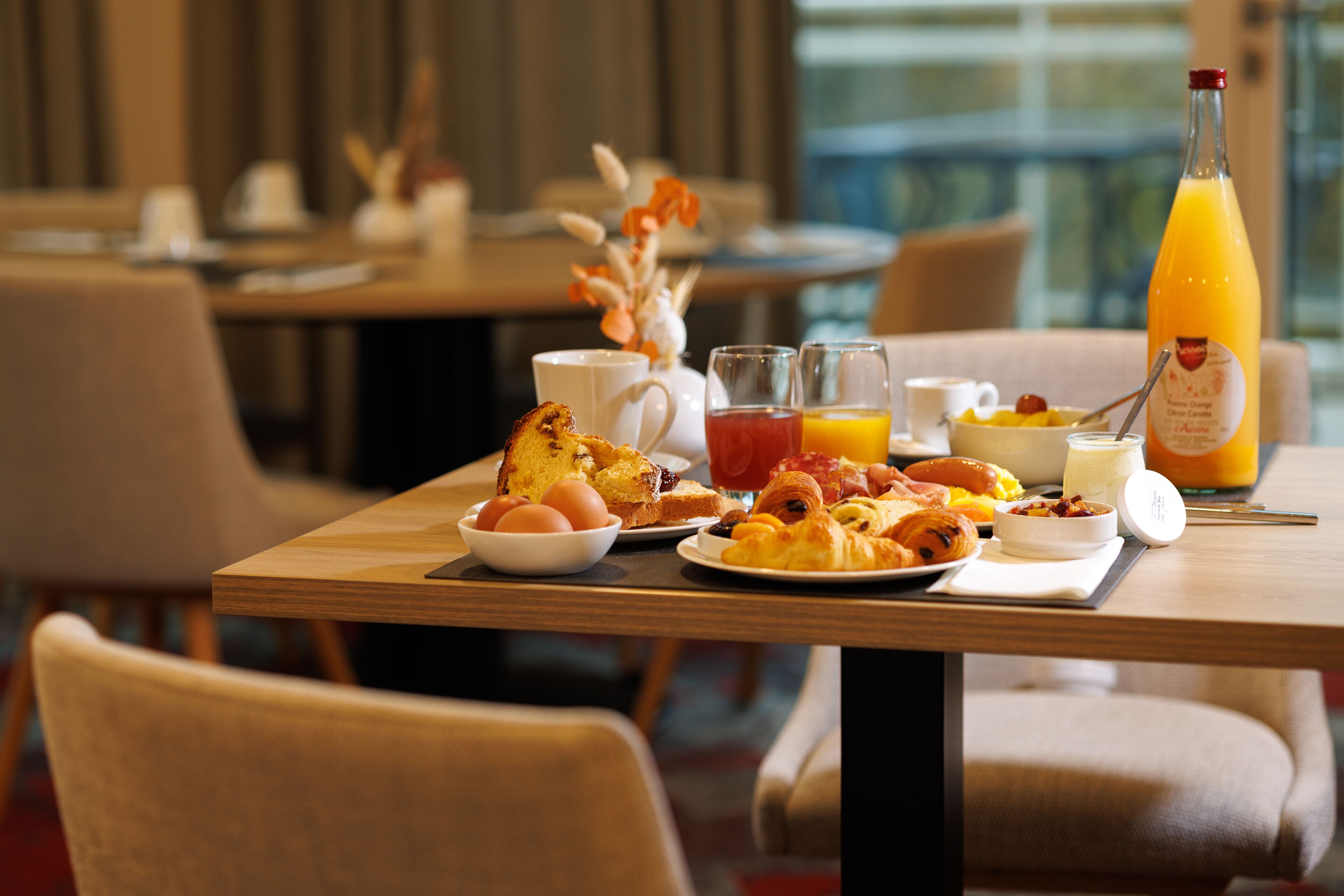 A breakfast table with eggs, toast, croissants, and juice in a hotel dining area.