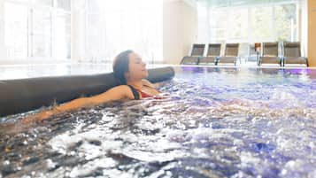 Una persona relajándose en un jacuzzi con vistas a la habitación y a las ventanas.