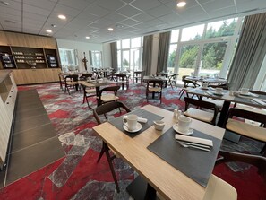 A modern hotel dining area with multiple tables and chairs, a coffee station, and large windows offering a view of the outdoors. - Hotel SPA Husseren Collections - Proche Colmar - Eguisheim (Husseren-les-Chateaux)