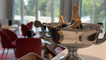 A silver champagne bucket on a table with two bottles of champagne inside. The bucket has the word "Champagne" engraved on it.