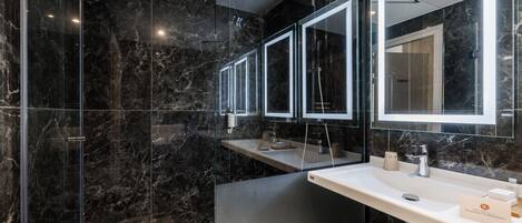 A modern bathroom with a glass-enclosed shower, a large mirror, and a white sink.