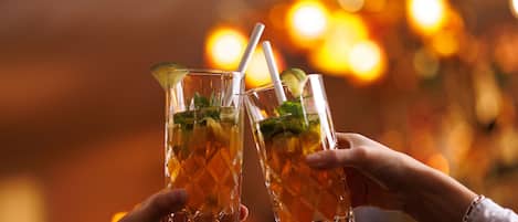 Due mani che sorreggono bicchieri con una bevanda, probabilmente in un bar.