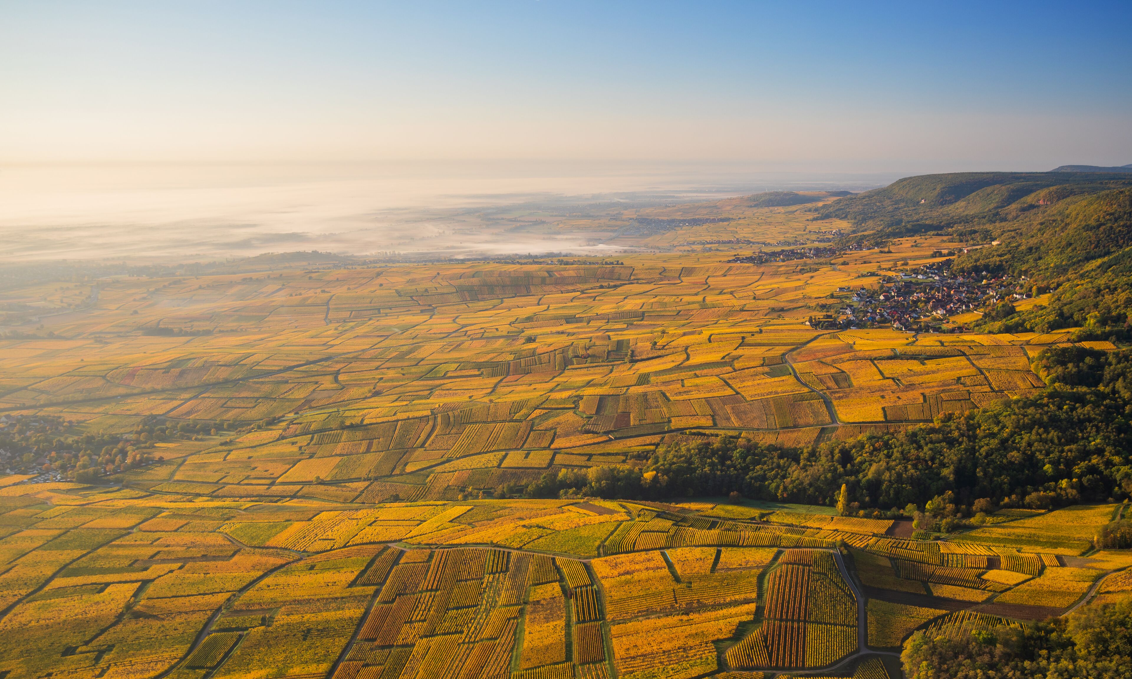 Vista aérea de un paisaje rural con campos en terrazas y un pequeño pueblo.