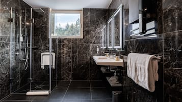 Ein modernes Badezimmer mit einer Glaskabine zur Dusche, einem Waschbecken inklusive Spiegel und einem Handtuchhalter.