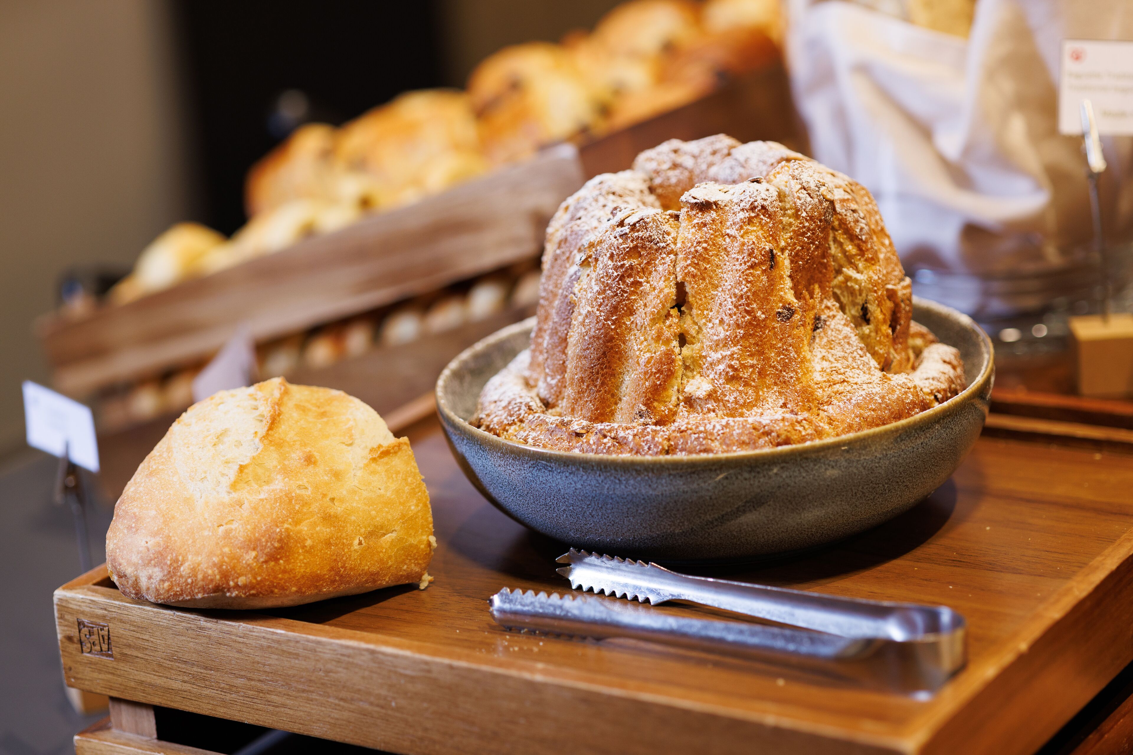 Un plateau de service en bois avec un gâteau en forme de couronne et une miche de pain.