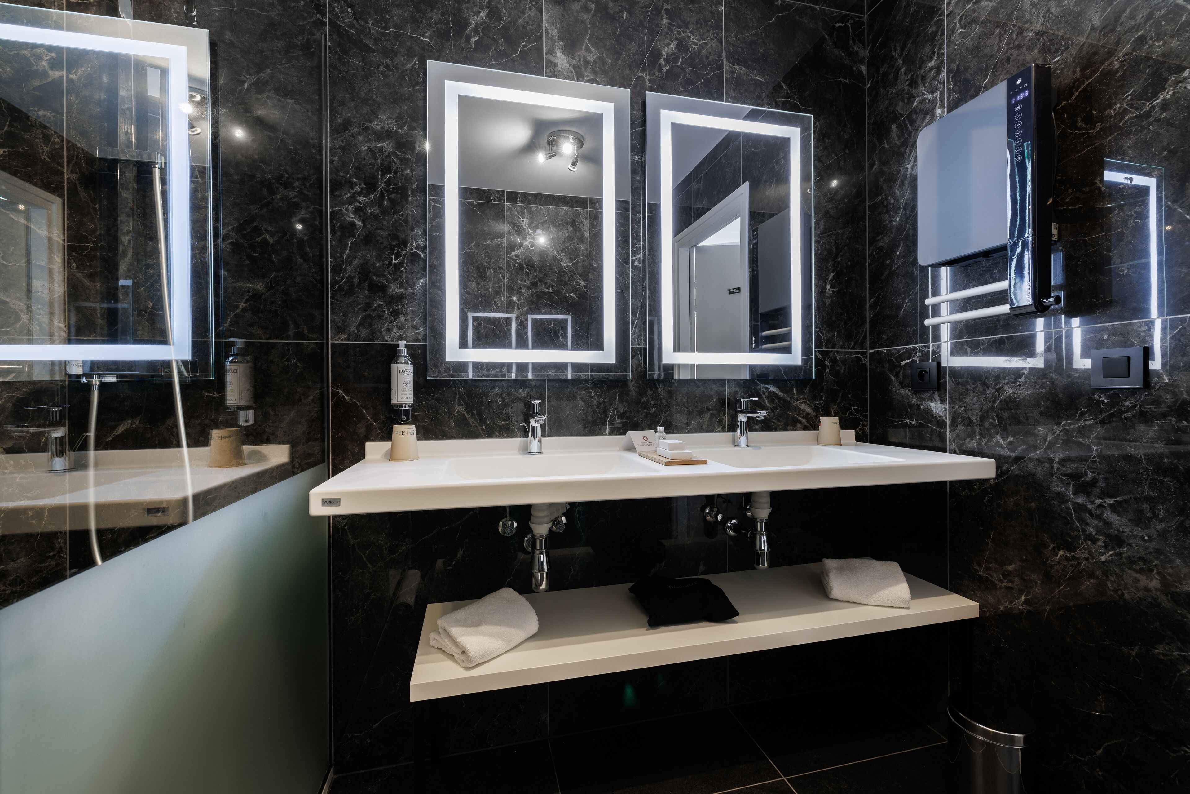 Un baño moderno con un espejo grande, dos lavamanos y una ducha integrada.