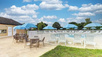 Een seizoensgebonden buitenzwembad en ligstoelen