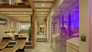 Un espace spa avec des chaises longues en bois, un comptoir d’accueil et un mur éclairé de lumière violette.