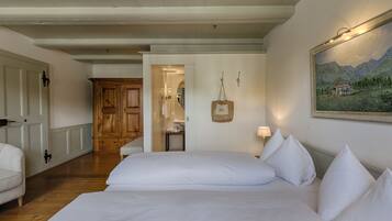 Habitación de hotel con una cama grande, un armario de madera, un baño con espejo y un cuadro en la pared.