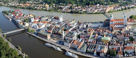 An aerial view of a riverside town with historic buildings, a bridge, and boats docked along the river.