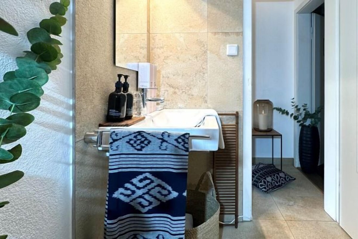 A bathroom with a white sink, a towel, a plant, and a mirror.