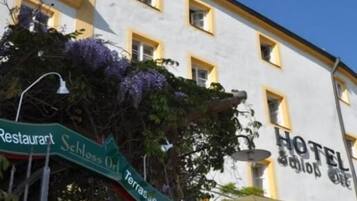 Un hotel con un letrero que indica un restaurante llamado 'Schloss Orl' y una terraza.