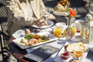 A table set for breakfast with a variety of foods, including meats, vegetables, and bread, along with drinks and a candle. - JUFA Hotel Wangen im Allgäu (Wangen im Allgäu)