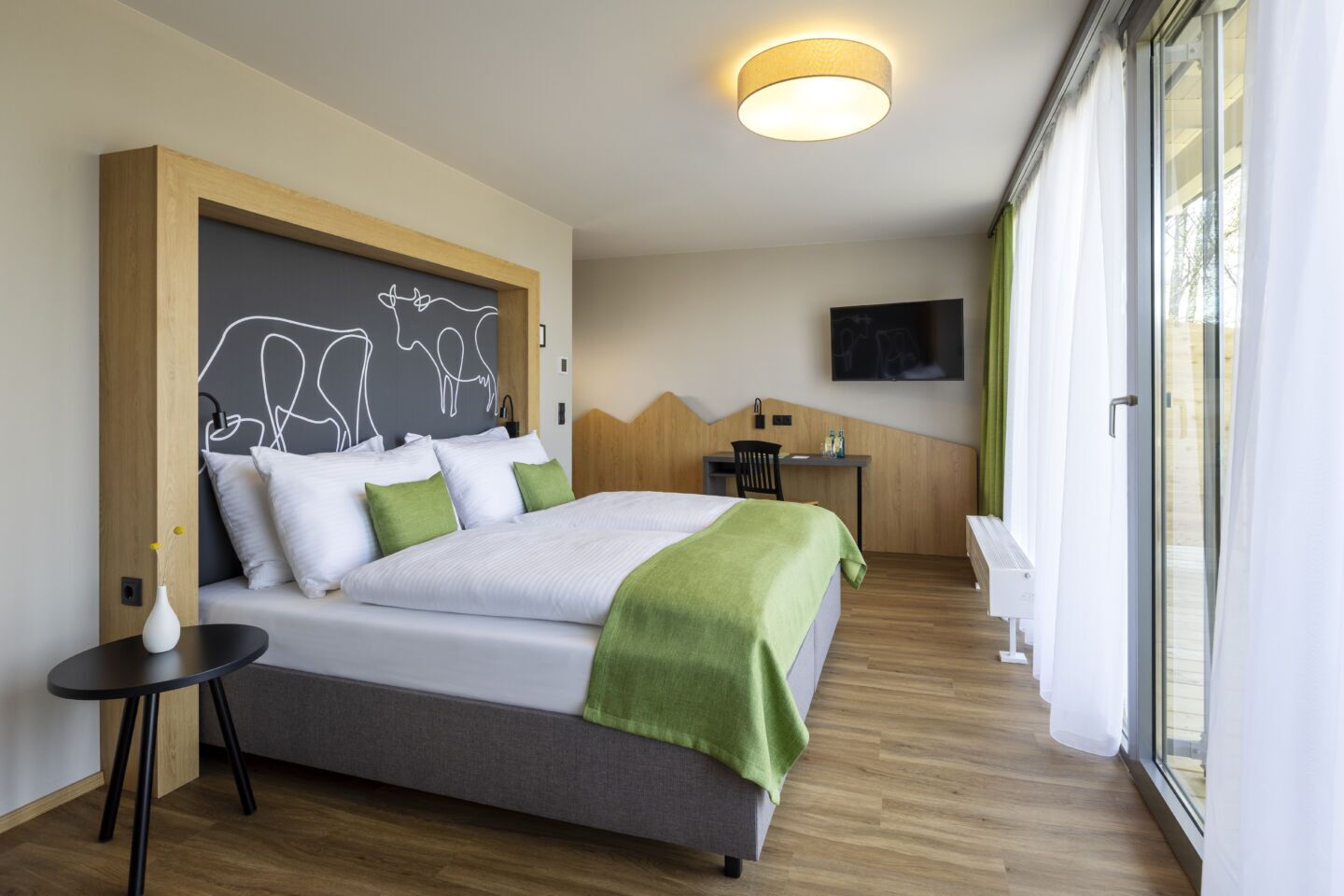 Ett modernt hotellrum med en stor säng, ett skrivbord och en TV.