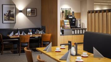 Um restaurante com cabines e mesas, uma máquina de café e um quadro de menu.