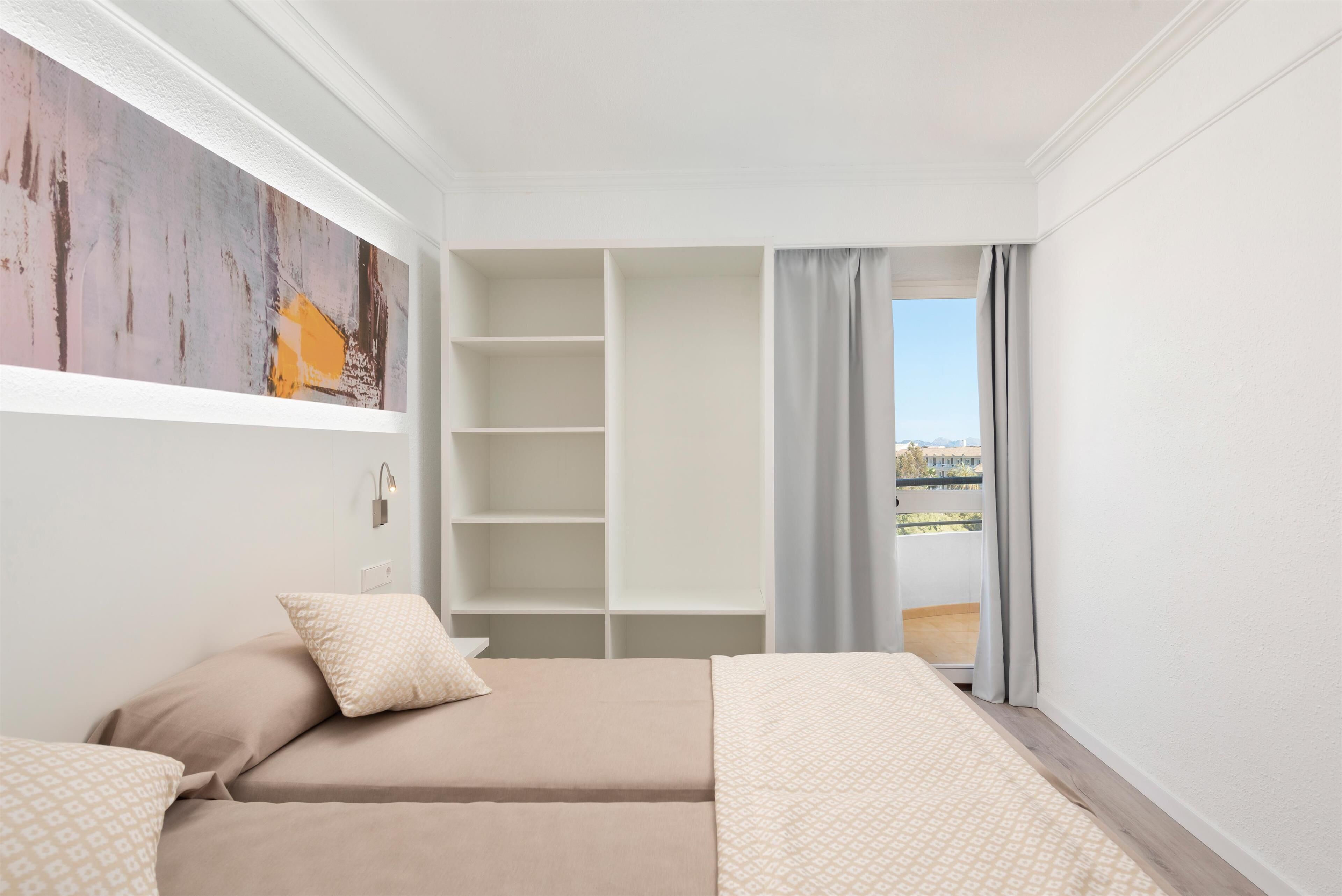 A bedroom with a bed, a large window, and a view of the city.