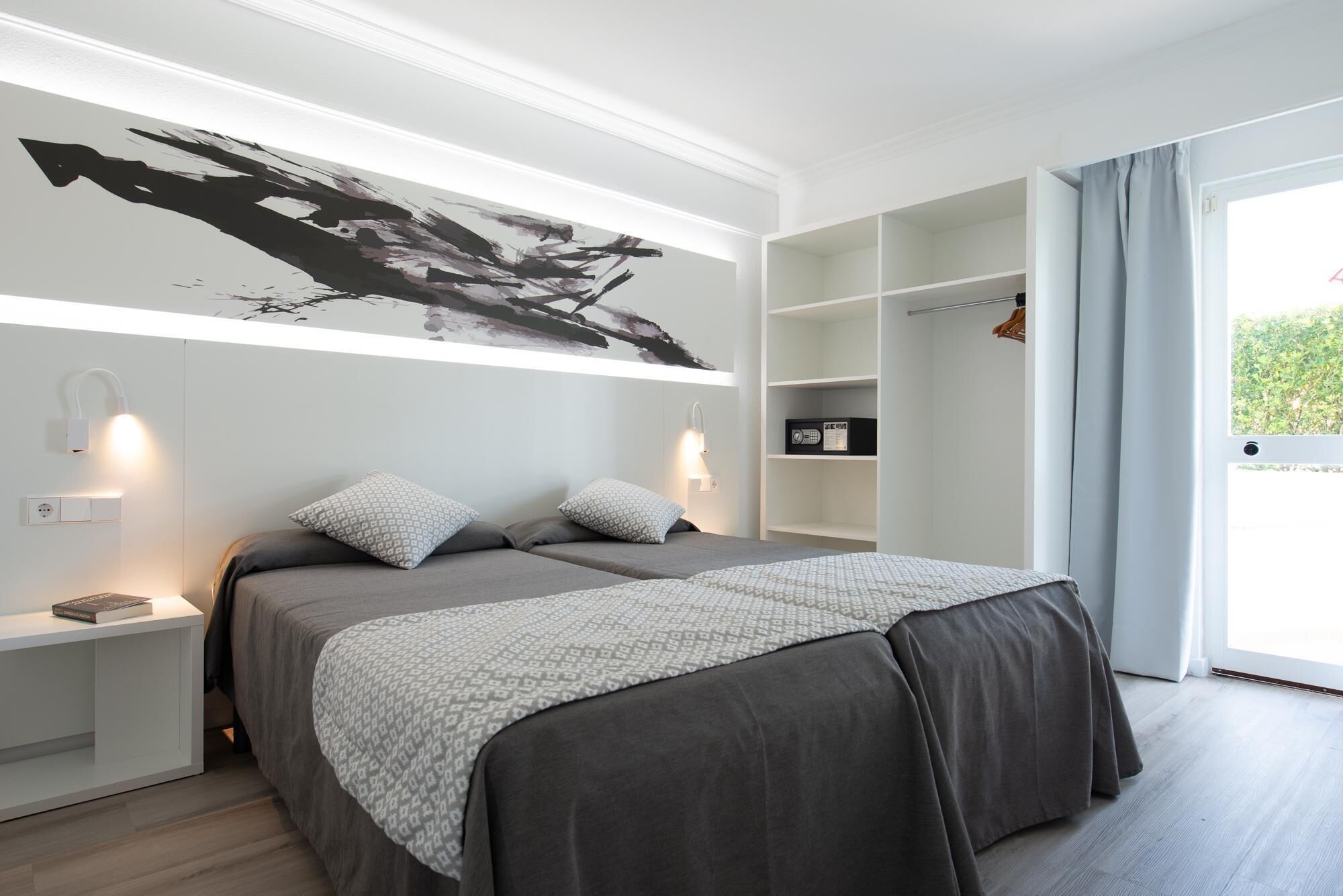 A modern bedroom with a large bed, bedside tables, a wall-mounted artwork, and a built-in shelving unit.